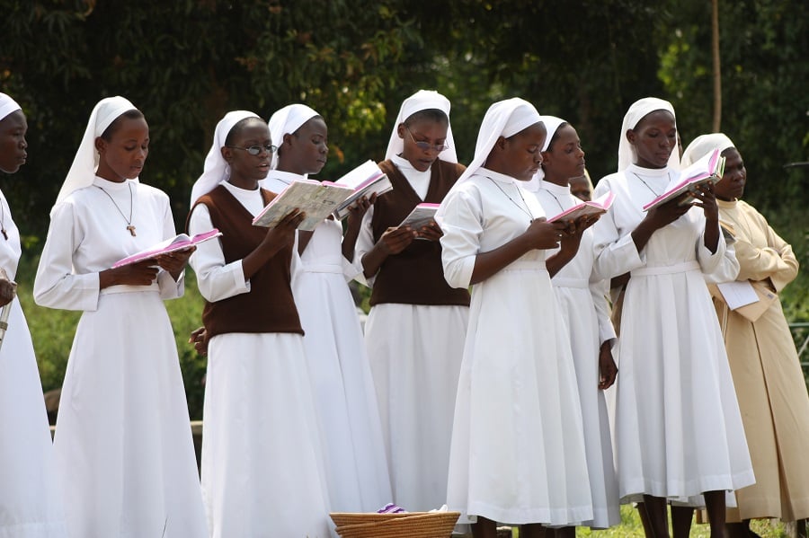 Choir sings as mourners drop flowers on the grave of Sr. John Battista