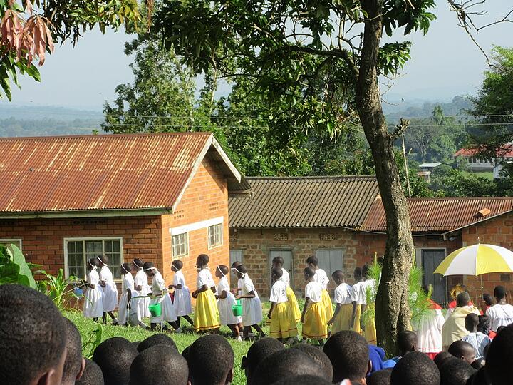The procession was led by primary school girls in white dresses carrying green buckets filled with flower petas and leaves which they sprinkled at various locations.